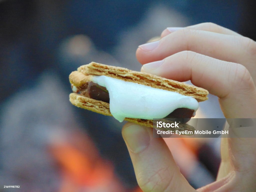 Close up of s'more with blurred firepit in background